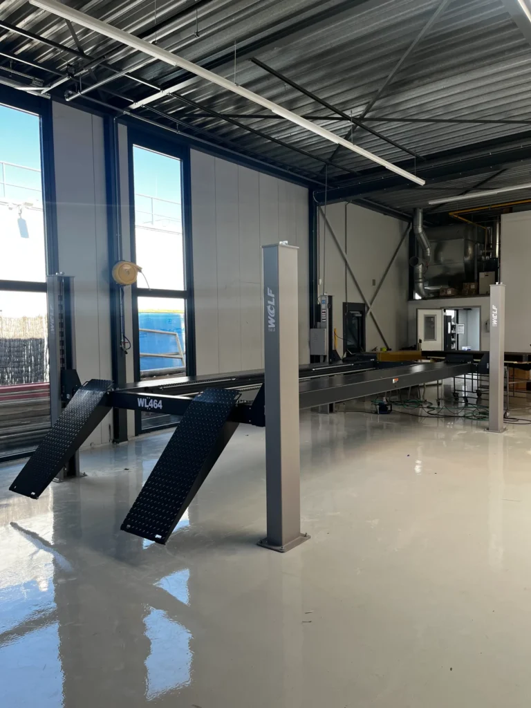 Leeuwis Equipment Wolf WL464L 4-Kolomshefbrug 5,65 Meter Rijbaanlengte - Vooraanzicht Van Een Grijze Volvo SUV Geparkeerd Op De Lange Rijbanen In Werkplaats